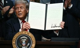 Trump holds up an executive order after signing it on Aug. 5, 2025. Two days later he signed the Improving Oversight of Federal Grantmaking executive order.