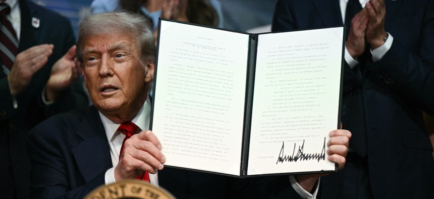 Trump holds up an executive order after signing it on Aug. 5, 2025. Two days later he signed the Improving Oversight of Federal Grantmaking executive order.