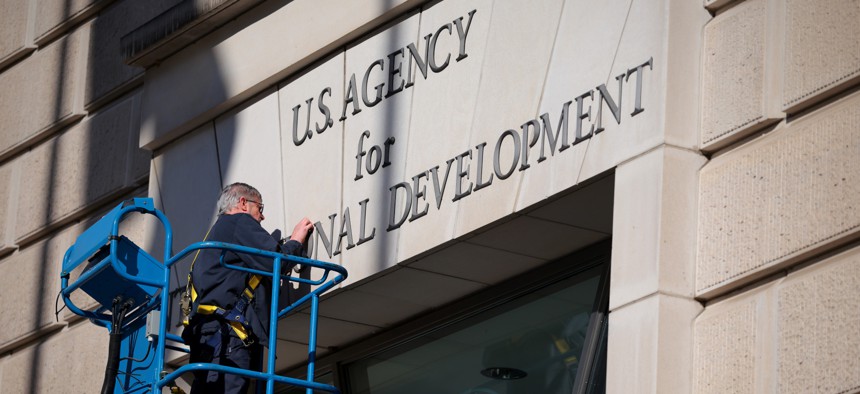 A worker removes the U.S. Agency for International Development sign on their headquarters on Feb. 7, 2025 in Washington, D.C. The agency's closure, alongside its Bureau of Conflict Prevention and Stabilization, marked the beginning in a reduction of federal terror prevention efforts.