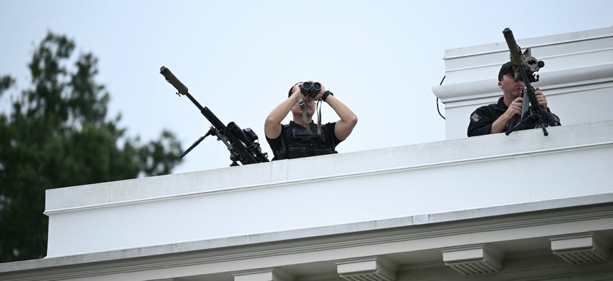 Members of the Secret Service's counter sniper team look out from the roof of the West Wing of the White House on Aug. 5, 2025.