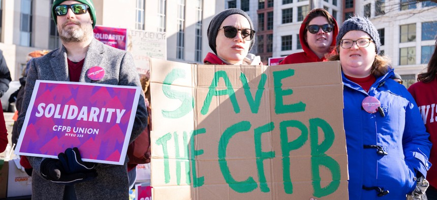 Demonstrators protest against cuts to the Consumer Financial Protection Bureau (CFPB) by Donald Trump and Elon Musks's DOGE initiative at the E. Barrett Prettyman United States Federal Court House in Washington, DC, on March 3, 2025. President Donald Trump’s efforts to crack down on banks’ alleged discrimination against conservative customers could be frustrated by his administration’s dismantling of a federal agency that protects consumers in the financial system.
