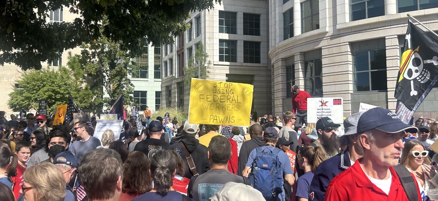 An individual at a 'No Kings' protest in Washington, D.C., on Saturday holds a sign that reads "Stop using federal workers as pawns."