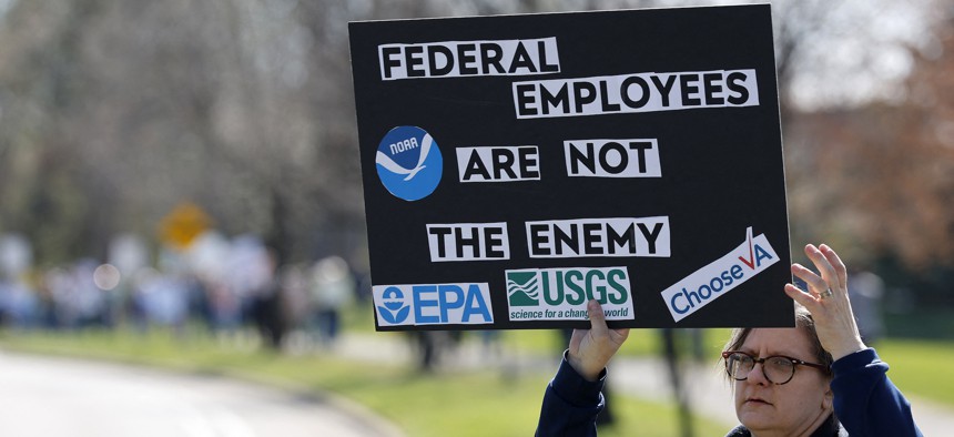 A demonstrator holds a sign during a rally outside the EPA offices in Ann Arbor, Michigan, on April 22, 2025. The Trump administration has sought to reduce the size of the federal workforce.