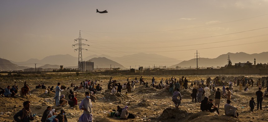 A military transport plane launches while Afghans who cannot get into the airport to evacuate, watch while stranded outside, in Kabul, Afghanistan, Aug. 23, 2021.