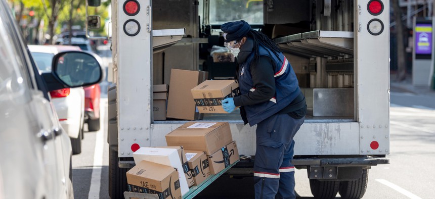A U.S. Postal Service worker delivers packages on April 28, 2020, in New York City. The postal agency is planning to begin auctioning access to its last-mile delivery network in early 2026.
