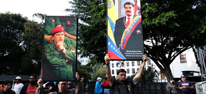 Supporters of Nicolas Maduro and late Hugo Chavez hold posters with their images after explosions and low-flying aircraft were heard on Jan. 3, 2026, in Caracas, Venezuela. 