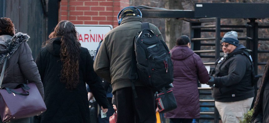 Federal employees walk to an entrance of the Navy Yard in Washington, D.C., as security checks credentials on Feb. 10, 2025, when many government workers were required to return to work in the office following a directive from President Donald Trump.