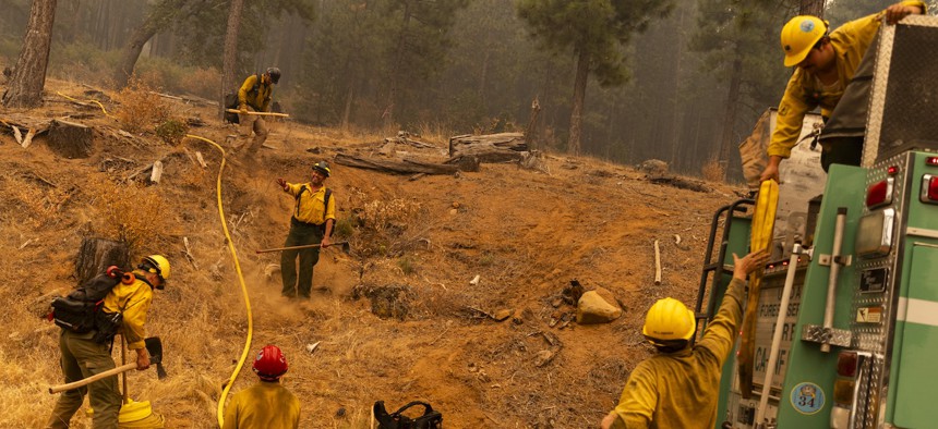 Firefighters with the U.S. Forest Service prepare a hoselay on a hillside during the Park Fire in Tehama County, Calif., on July 27, 2024.