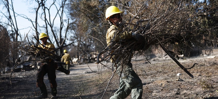  U.S. Forest Service firefighters from Porterville, California, clear away downed branches from a home which burned in the Eaton Fire on Jan. 17, 2025 in Altadena, California.