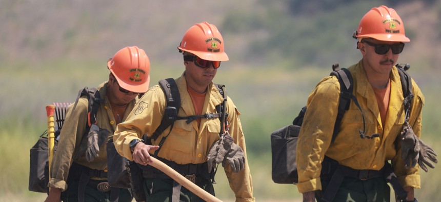 U.S. Forest Service firefighters walk as the Post Fire burns through Castaic, California, June 16, 2024. The Trump administration is proposing to consolidate multiagency federal firefighting operations into a single agency, but does not have funding to do so. 