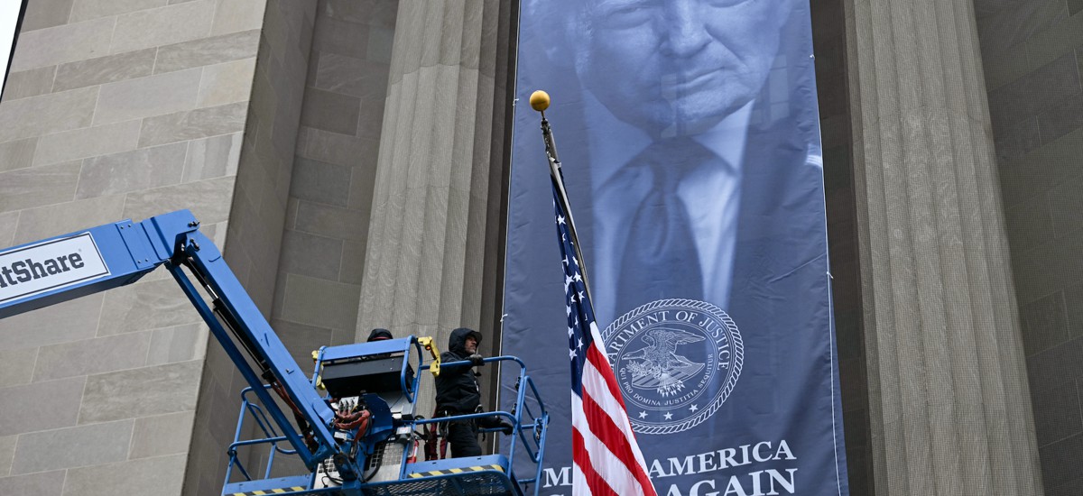 Workers install a banner featuring President Donald Trump on the facade of the Justice Department headquarters in Washington, D.C, on Feb. 19. 