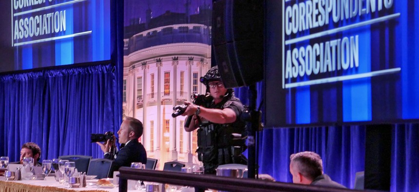 Getty Images photographer Andrew Harnik takes photos as agent points his weapon after an incident at the annual White House Correspondents Association Dinner on April 25, 2026 in Washington, D.C. According to reports, President Donald Trump, along with other government officials, were evacuated from the Washington Hilton.