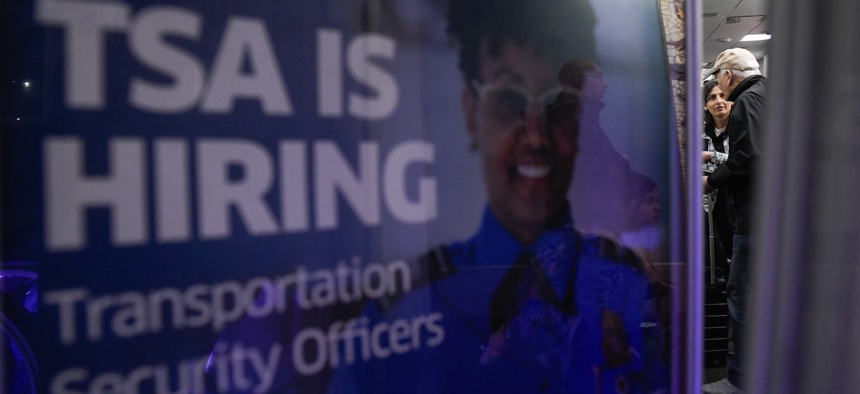 A poster promoting a career in TSA sits by a crowded TSA Checkpoint at the Philadelphia International Airport on March 28, 2026.