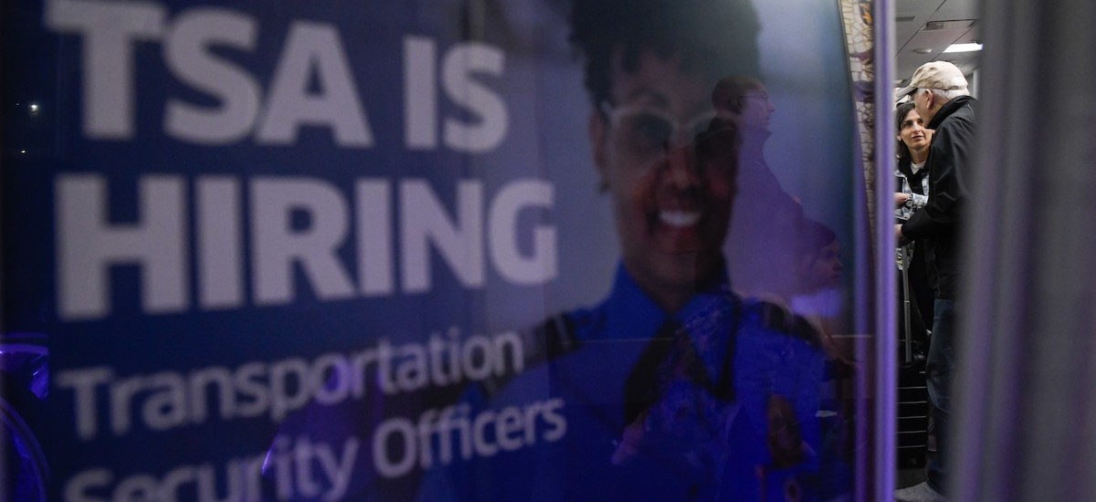 A poster promoting a career in TSA sits by a crowded TSA Checkpoint at the Philadelphia International Airport on March 28, 2026.
