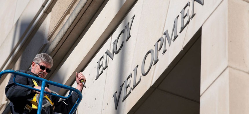 A worker removes the U.S. Agency for International Development sign on their headquarters on Feb. 7, 2025 in Washington, D.C. President Donald Trump and Elon Musk's Department of Government Efficiency (DOGE) abruptly shutdown the U.S. aid agency earlier this week leaving thousands unemployed and putting U.S. foreign diplomacy and aid programs in limbo. 