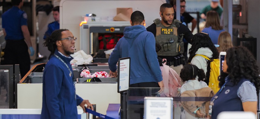 ICE agents assist travelers through security at BWI Airport on March 30, 2026 in Baltimore. ICE officers were deployed to airports during Transportation Security Administration staffing shortages this year. Newly public documents show TSA has been sharing passengers' personal information with ICE.