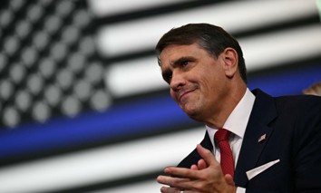 Attorney General Todd Blanche looks on as President Donald Trump delivers remarks in Garden City, N.Y., on Aug. 14. Public Citizen is arguing that a speech Blanche gave at the event violated the Hatch Act. 