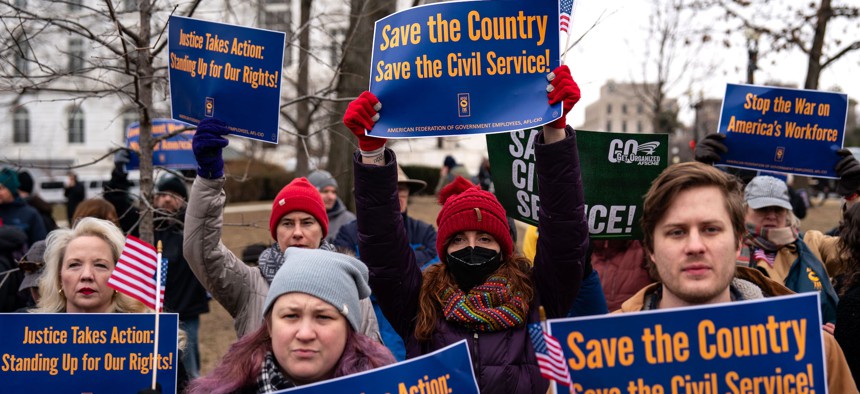 People hold signs during a "Save the Civil Service" rally outside the U.S. Capitol on Feb. 11, 2025. A new survey found that 44% of respondents said they trusted civil servants.