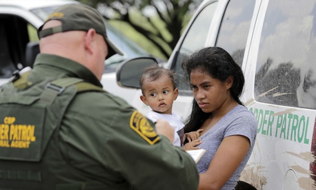 A mother migrating from Honduras holds her 1-year-old child as she surrenders to U.S. Border Patrol agents after illegally crossing the border June 25, 2018, near McAllen, Texas.
