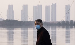 A man wears a face mask as he stands along the waterfront in Wuhan in central China's Hubei Province, which is at the center of the Coronavirus outbreak. 