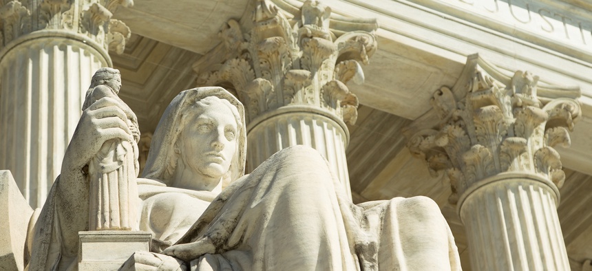 A statue of lady justice sits in front of a courthouse