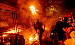 Protesters throw flaming debris over a fence at the Mark O. Hatfield United States Courthouse on July 22 in Portland, Ore. Following a larger Black Lives Matter Rally, several hundred demonstrators faced off against federal officers at the courthouse.