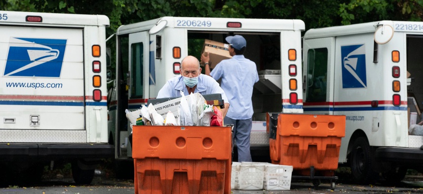 Letter carriers load mail trucks for deliveries at a U.S. Postal Service facility in McLean, Va., on July 31. 