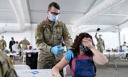 Leanne Montenegro, 21, covers her eyes as she doesn't like the sight of needles, while she receives the Pfizer COVID-19 vaccine at a FEMA vaccination center at Miami Dade College in Miami. 